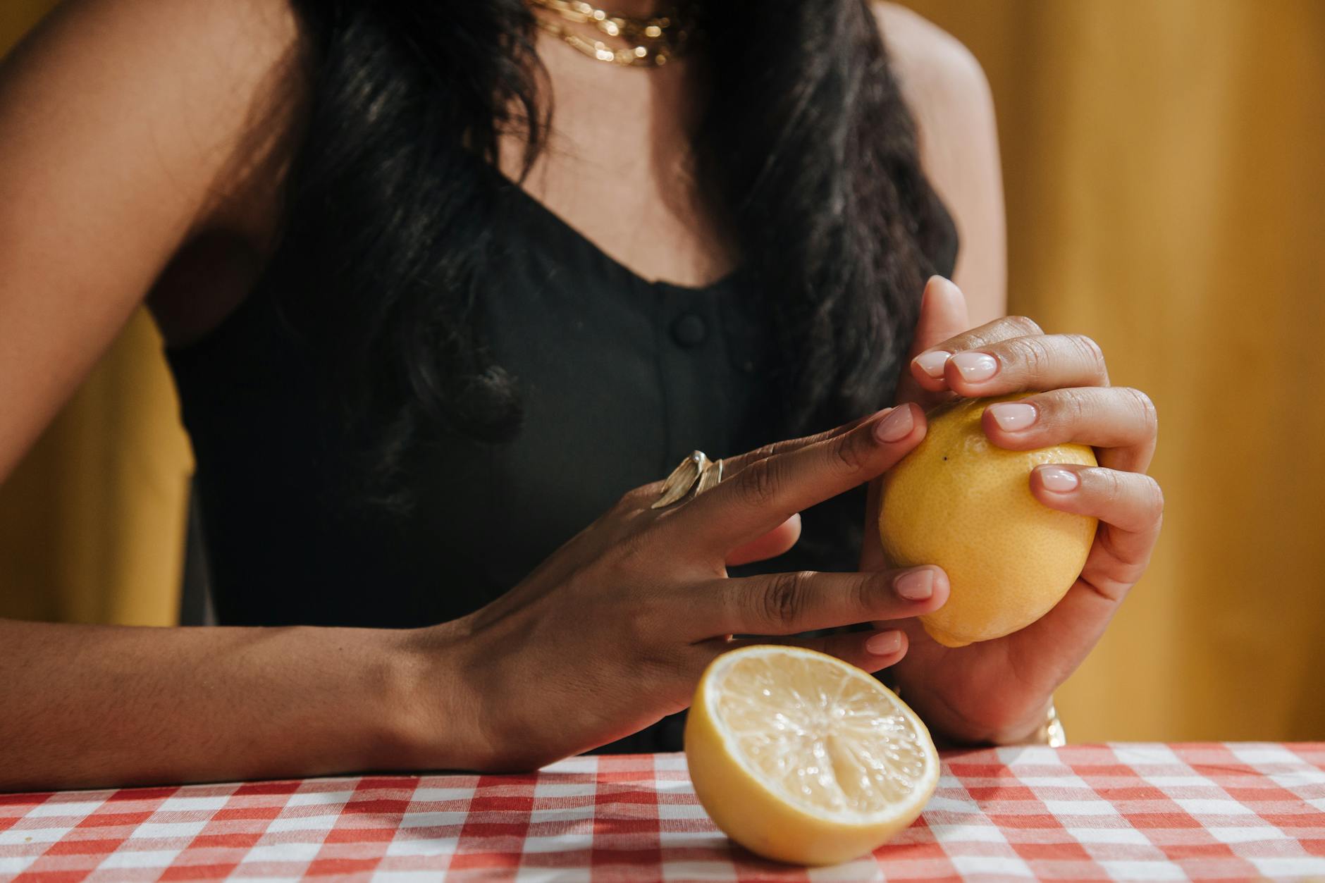 A person holding a pink clitoral vibrator against an intimate bedroom background