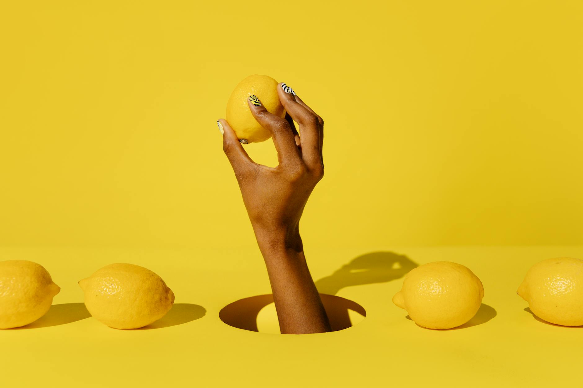 A hand holding a lemon against a vivid yellow background, symbolizing fresh starts and reconnection
