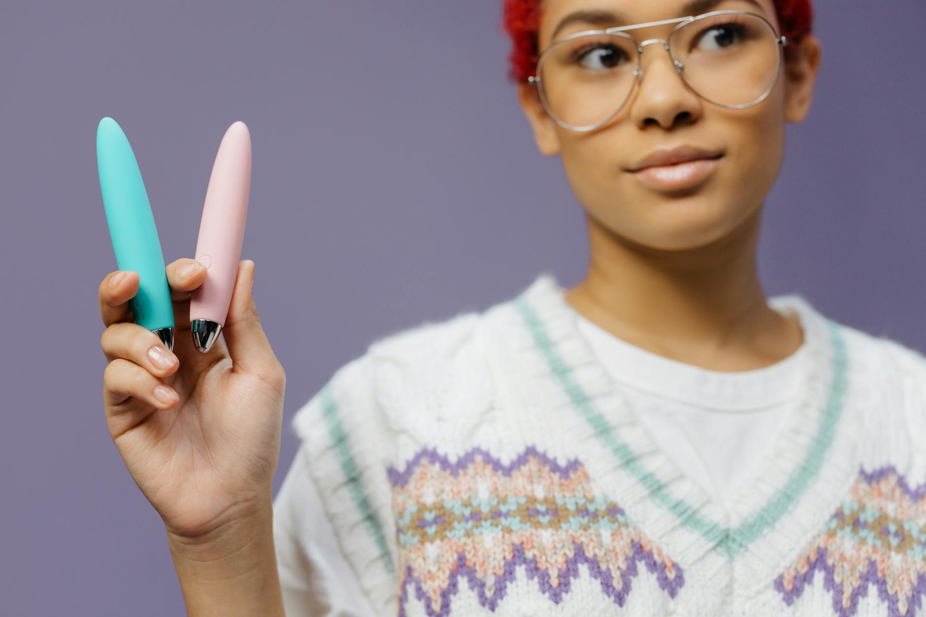 Woman holding lemon vibrators against a purple background, expressing openness to intimate exploration