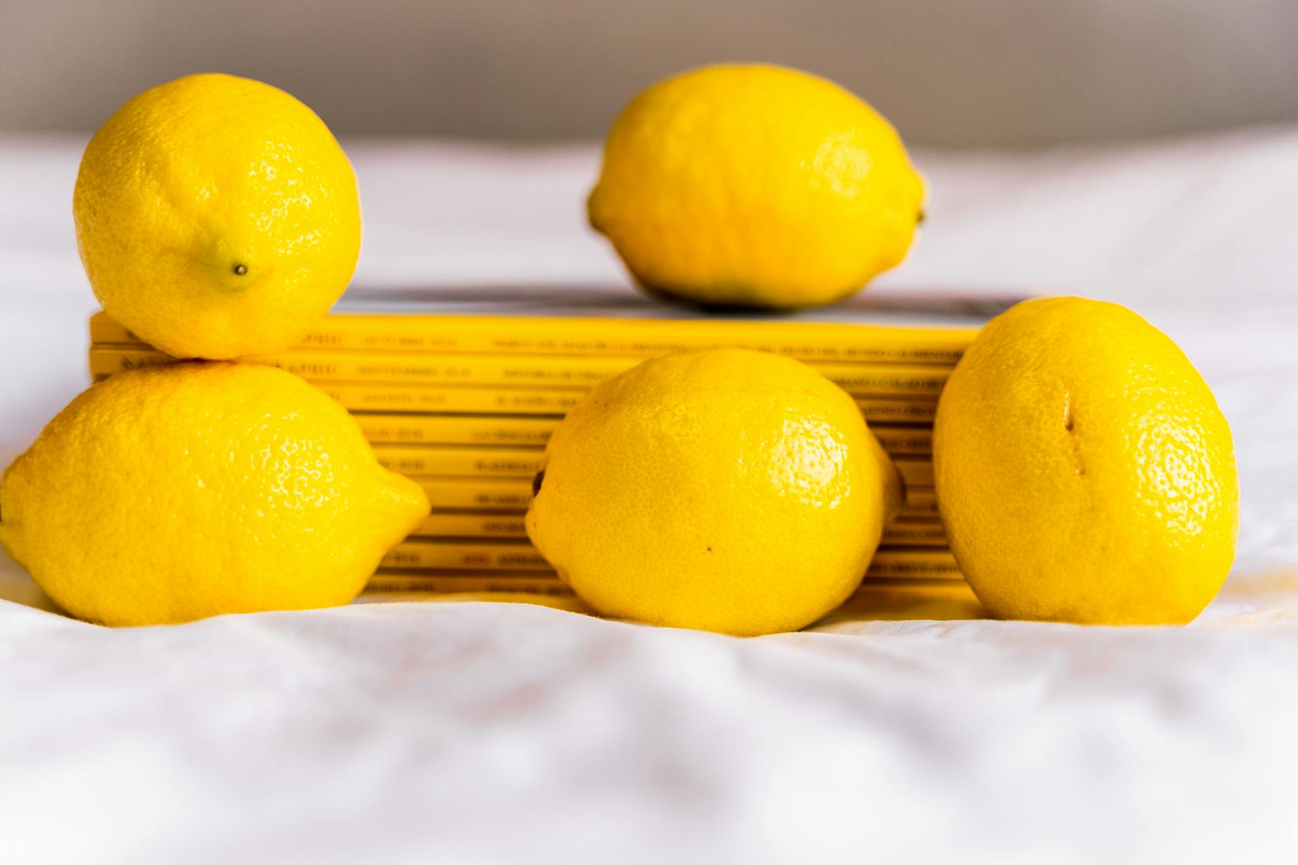 Fresh lemons on white tablecloth with stacked books, symbolizing slow, intentional buildup